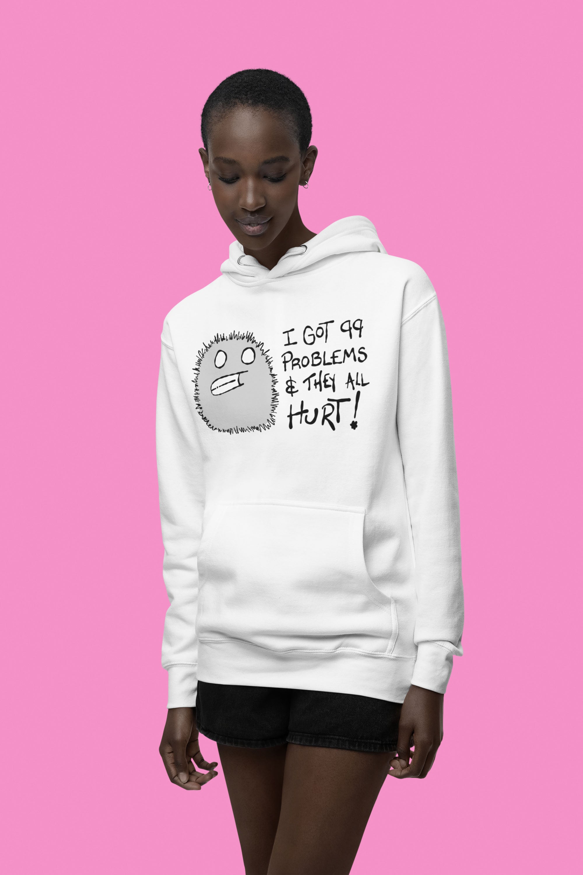 A person wearing a white hoodie with a cartoon monster character and text I got 99 problems and they all hurt, standing in front of a pink background