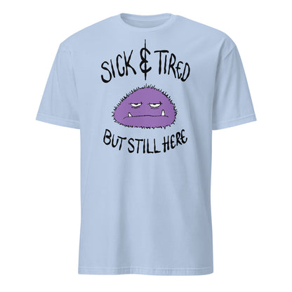 Light blue t-shirt with a purple cartoon character and text sick and tired but still here on a white background